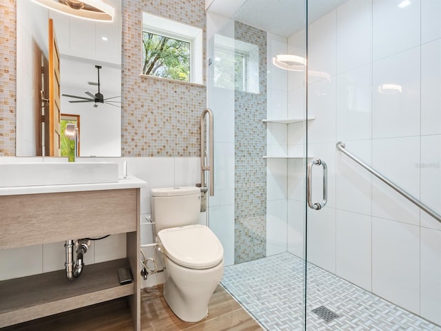 bathroom with ceiling fan, walk in shower, wood-type flooring, toilet, and tile walls