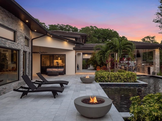 patio terrace at dusk with a fire pit and exterior kitchen