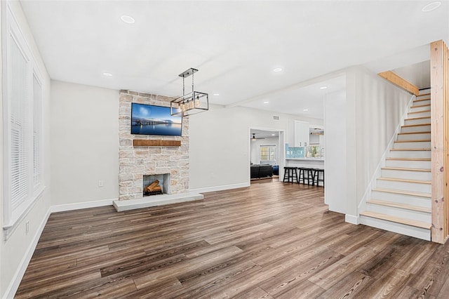 unfurnished living room with hardwood / wood-style floors, a healthy amount of sunlight, and a stone fireplace