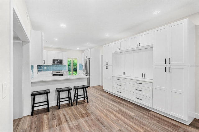 kitchen with kitchen peninsula, a breakfast bar, white cabinets, and stainless steel appliances