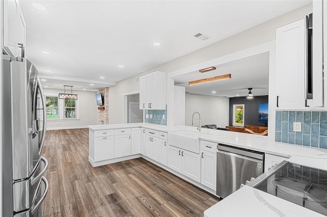 kitchen with kitchen peninsula, stainless steel appliances, light stone counters, and sink