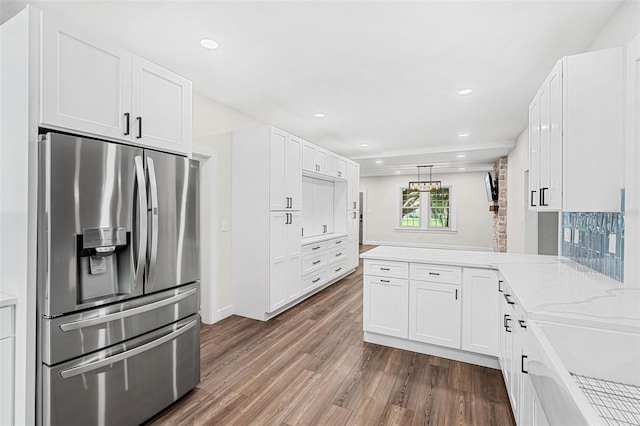 kitchen with stainless steel fridge, wood-type flooring, white cabinetry, and kitchen peninsula