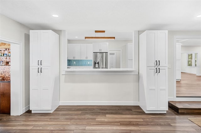 kitchen with stainless steel fridge, hardwood / wood-style floors, and white cabinets