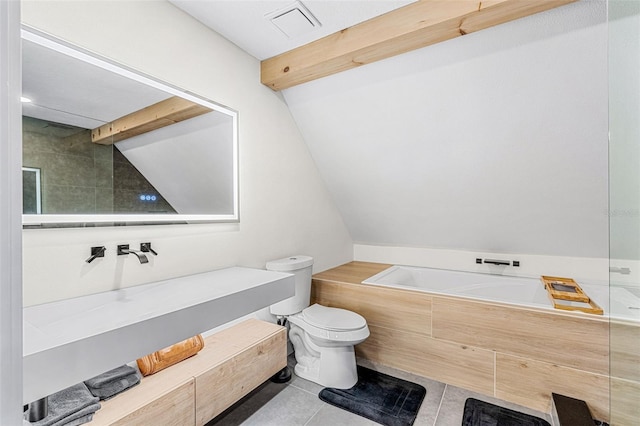 bathroom with tile patterned floors, tiled bath, lofted ceiling with beams, and toilet