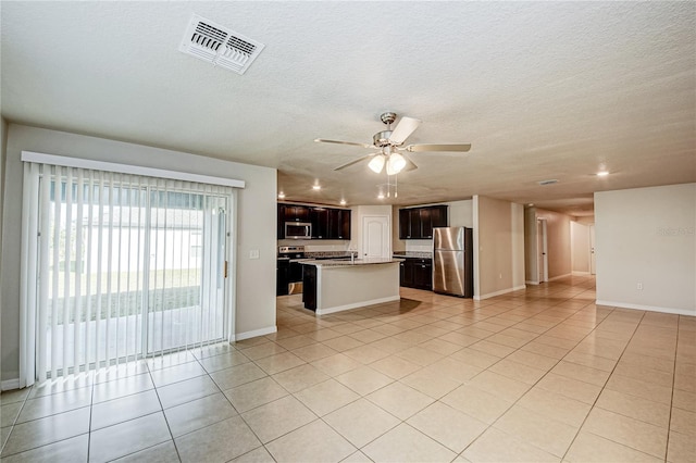 kitchen with light tile patterned flooring, stainless steel appliances, ceiling fan, and a center island with sink