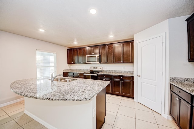 kitchen with light tile patterned flooring, an island with sink, appliances with stainless steel finishes, and sink