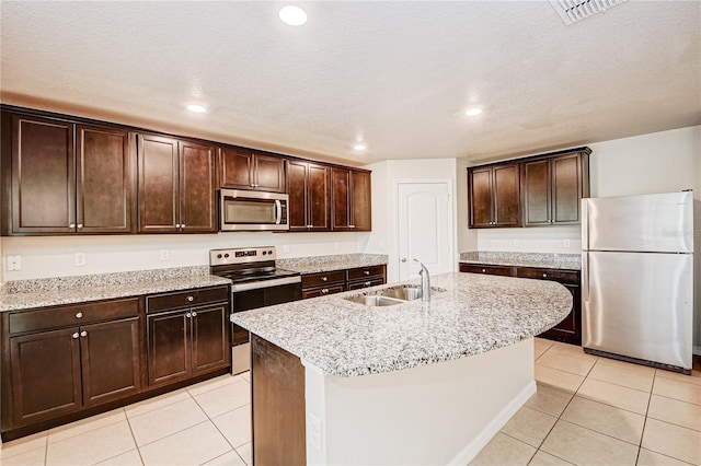 kitchen featuring an island with sink, appliances with stainless steel finishes, sink, and light tile patterned floors