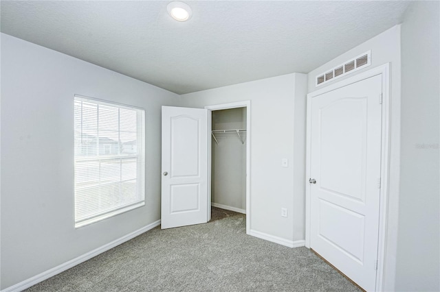 unfurnished bedroom with a closet, light carpet, and a textured ceiling