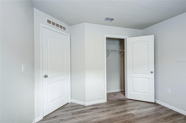 unfurnished bedroom with hardwood / wood-style flooring, a closet, and a textured ceiling