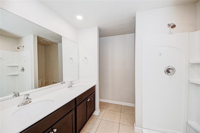 bathroom featuring tile patterned flooring, vanity, and a shower