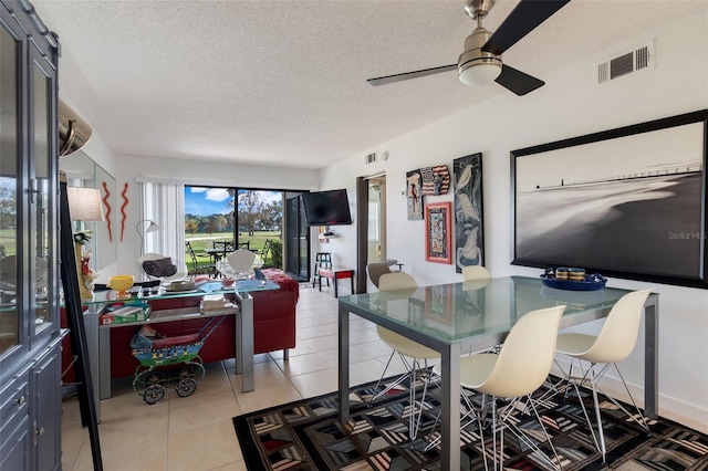 tiled dining space with ceiling fan and a textured ceiling