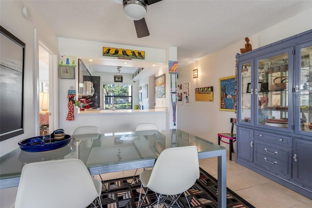 tiled dining space with a textured ceiling and ceiling fan