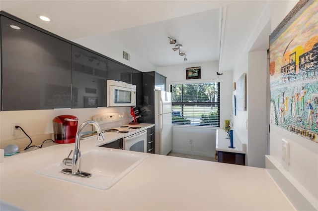 kitchen featuring kitchen peninsula, white appliances, and sink