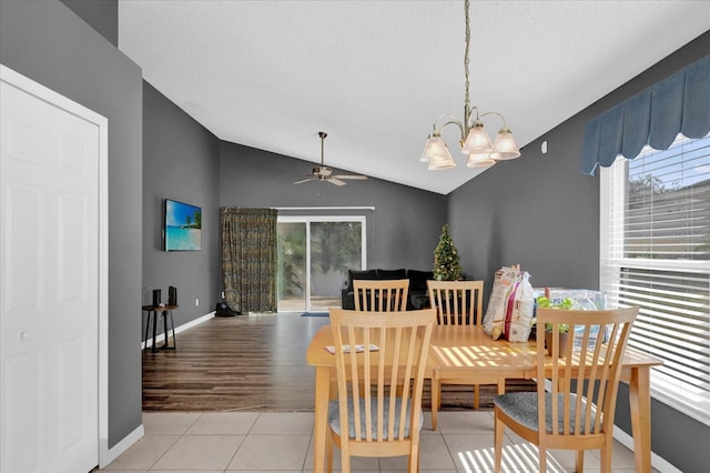 dining room featuring a wealth of natural light, ceiling fan with notable chandelier, lofted ceiling, and light wood-type flooring