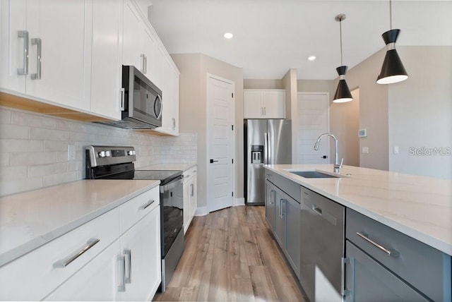 kitchen featuring sink, decorative backsplash, appliances with stainless steel finishes, decorative light fixtures, and white cabinetry