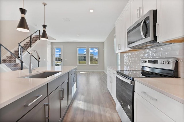 kitchen with decorative backsplash, stainless steel appliances, sink, pendant lighting, and white cabinets