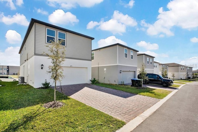 view of front of property featuring central AC, a front lawn, and a garage