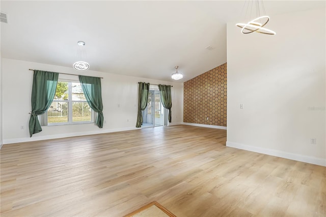 unfurnished living room with light wood-type flooring and an inviting chandelier