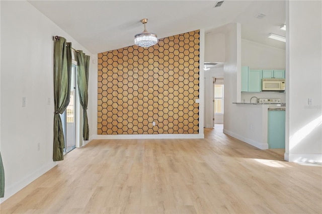 interior space featuring a notable chandelier, light hardwood / wood-style floors, and lofted ceiling