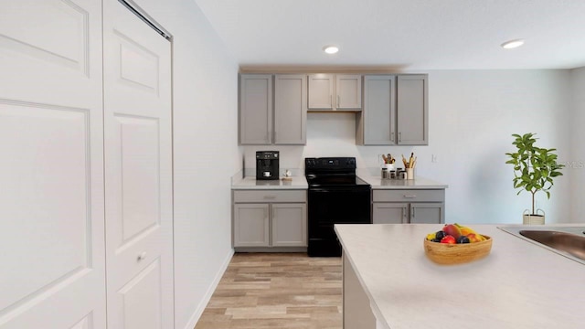 kitchen featuring light wood-type flooring, black range with electric cooktop, and gray cabinetry