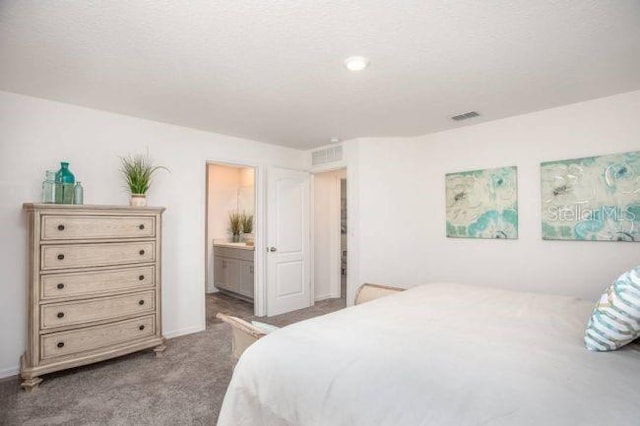 bedroom featuring ensuite bathroom and light colored carpet