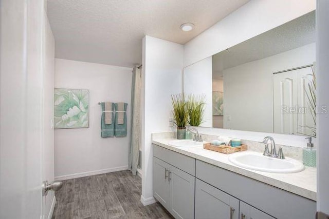 bathroom featuring wood-type flooring, vanity, and a textured ceiling