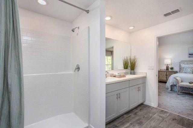 bathroom featuring tiled shower, wood-type flooring, and vanity