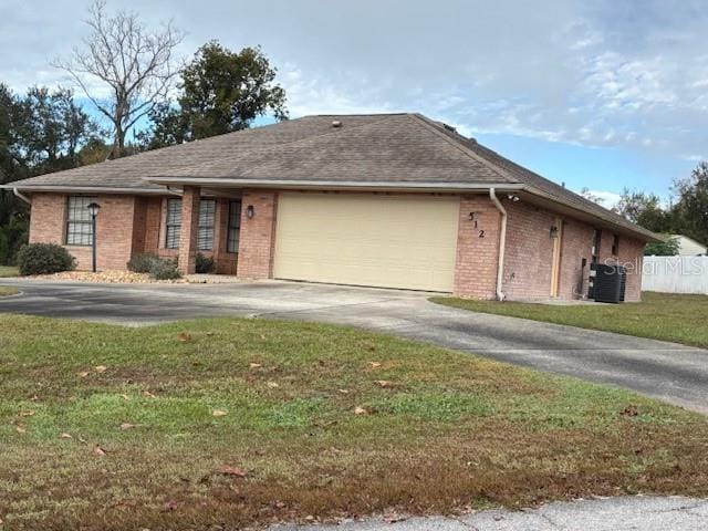 view of front of house featuring cooling unit, a garage, and a front lawn