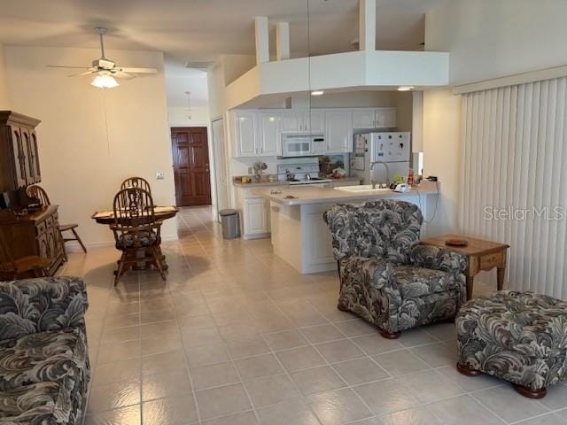 living room featuring ceiling fan, a towering ceiling, and light tile patterned floors