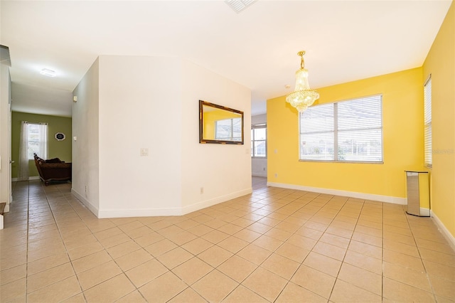 tiled empty room featuring a notable chandelier