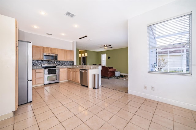 kitchen featuring stainless steel appliances, light tile patterned flooring, light brown cabinetry, and kitchen peninsula