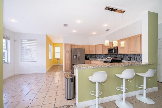 kitchen featuring pendant lighting, stainless steel appliances, a kitchen bar, light tile patterned flooring, and kitchen peninsula