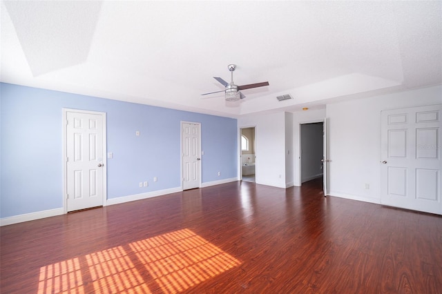 unfurnished room featuring a raised ceiling, dark hardwood / wood-style floors, and ceiling fan