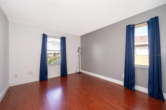 empty room featuring plenty of natural light and dark hardwood / wood-style flooring