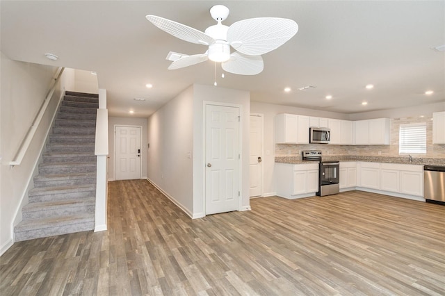 kitchen featuring ceiling fan, light hardwood / wood-style floors, white cabinetry, appliances with stainless steel finishes, and light stone counters