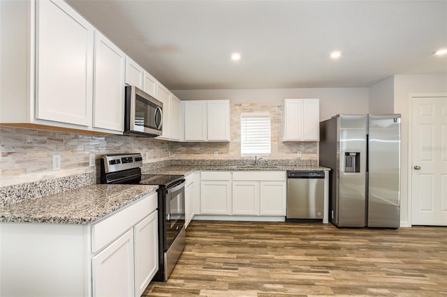 kitchen featuring light stone countertops, stainless steel appliances, white cabinetry, and sink