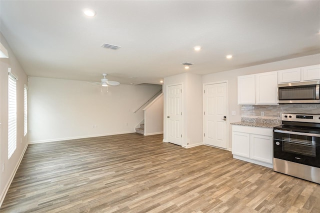 kitchen featuring backsplash, white cabinets, light wood-type flooring, and appliances with stainless steel finishes