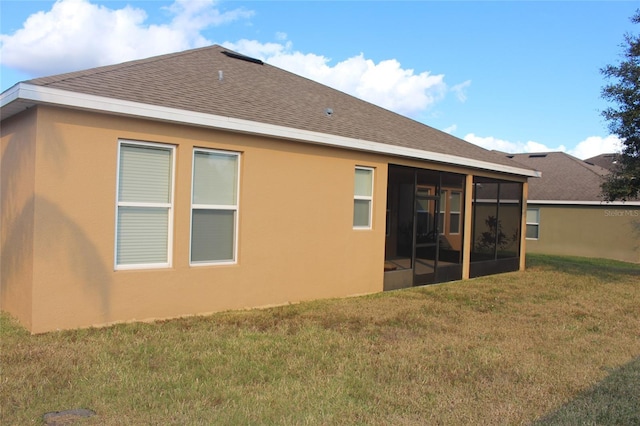 back of property featuring a sunroom and a lawn