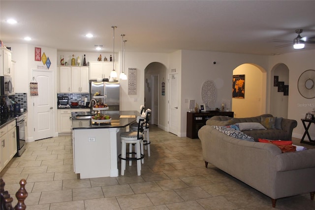 kitchen featuring decorative light fixtures, stainless steel appliances, a breakfast bar, and an island with sink