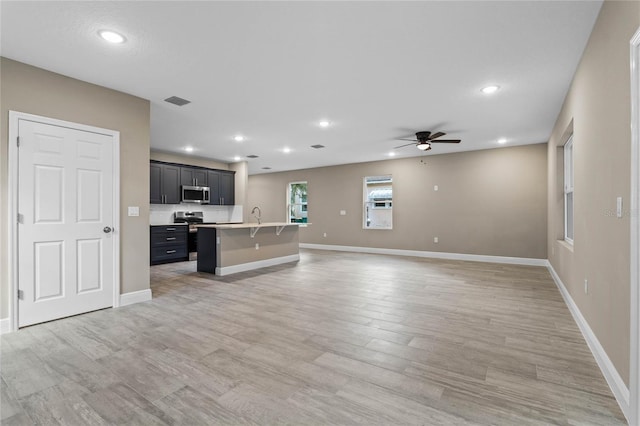 unfurnished living room with ceiling fan, hardwood / wood-style floors, and sink