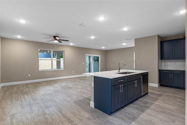 kitchen featuring a kitchen island with sink, sink, stainless steel dishwasher, ceiling fan, and light hardwood / wood-style floors