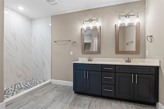 bathroom with tiled shower, wood-type flooring, and vanity