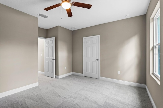 empty room with ceiling fan, light colored carpet, and a healthy amount of sunlight