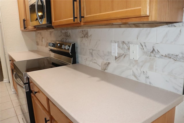 kitchen featuring decorative backsplash, light tile patterned floors, and stainless steel appliances