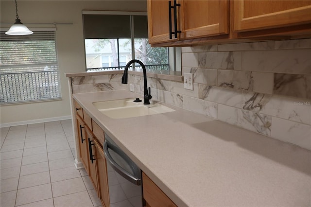 kitchen featuring pendant lighting, backsplash, sink, stainless steel dishwasher, and light tile patterned floors