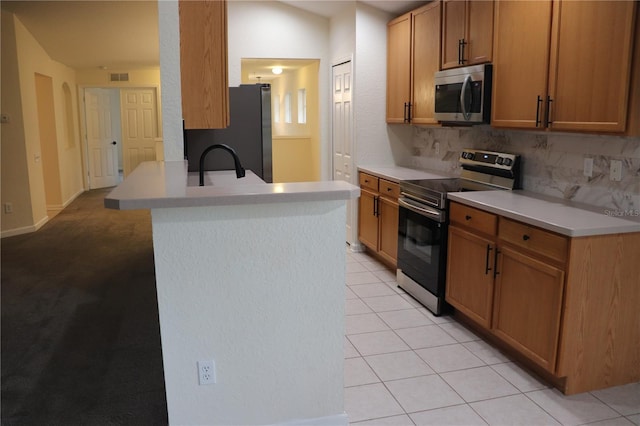 kitchen featuring backsplash, a kitchen island with sink, sink, light tile patterned floors, and appliances with stainless steel finishes