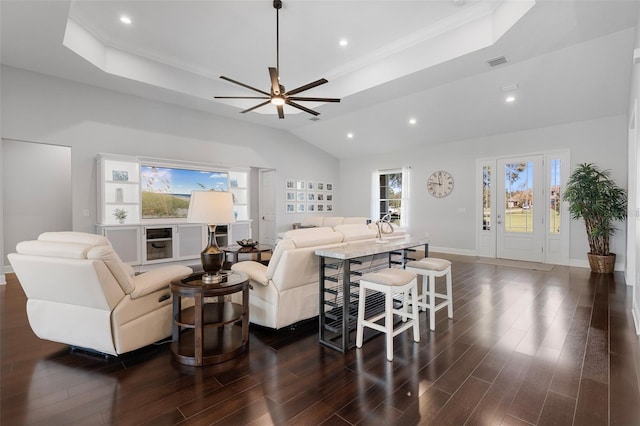 living room featuring lofted ceiling, crown molding, dark hardwood / wood-style floors, ceiling fan, and a tray ceiling