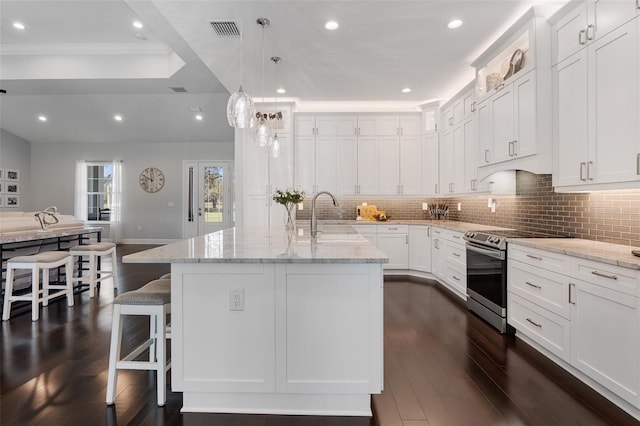 kitchen with stainless steel electric stove, light stone countertops, white cabinets, and dark hardwood / wood-style floors