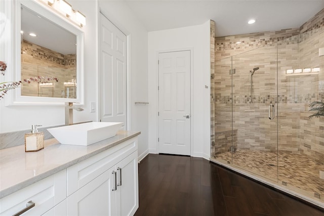 bathroom with hardwood / wood-style floors, vanity, and a shower with shower door