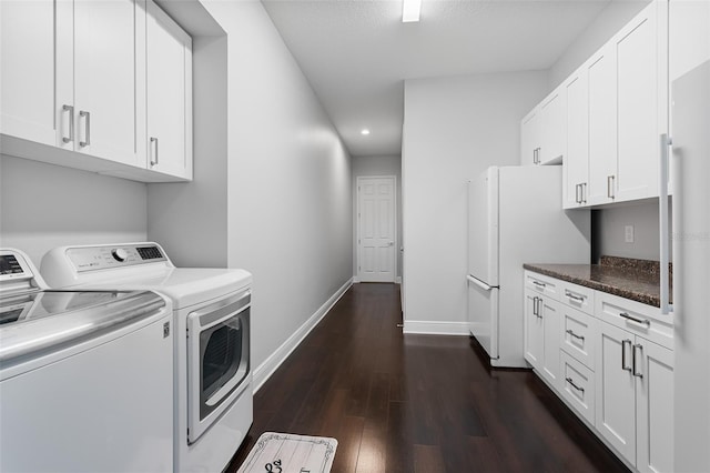 laundry room with a textured ceiling, washing machine and dryer, cabinets, and dark hardwood / wood-style floors